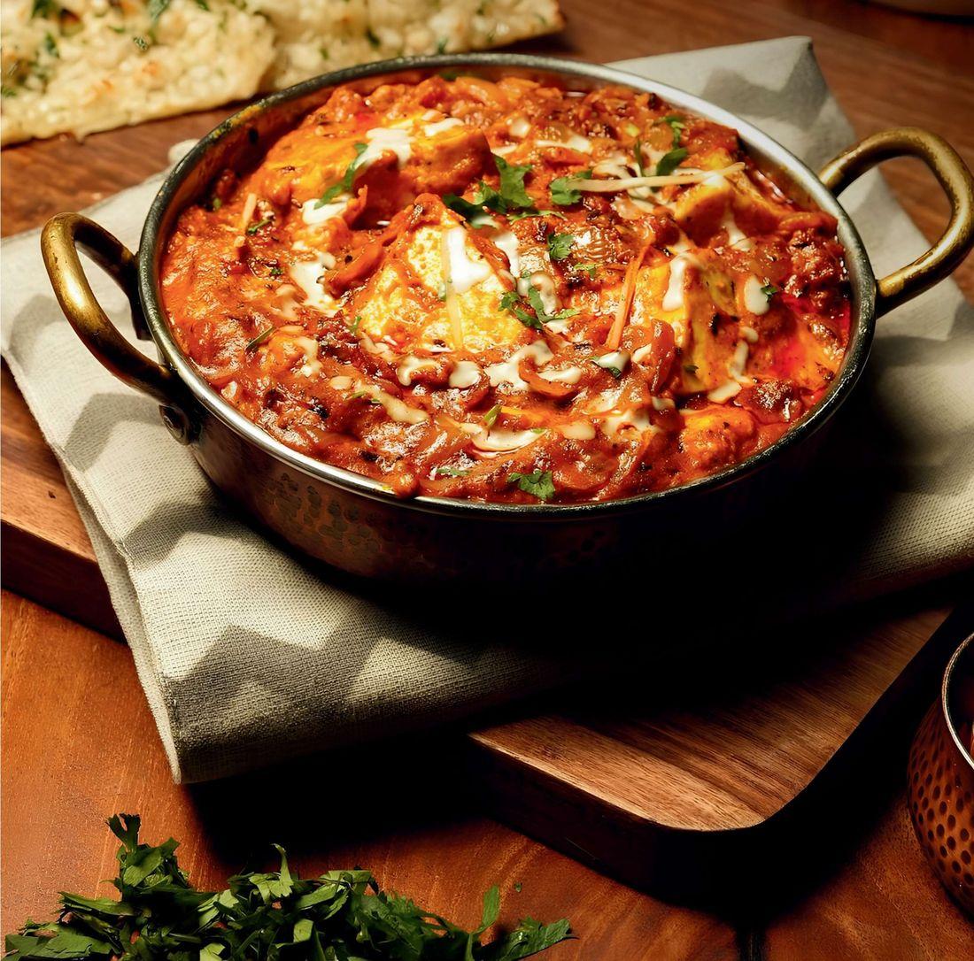 Paneer makhani in a copper handi with fresh naan